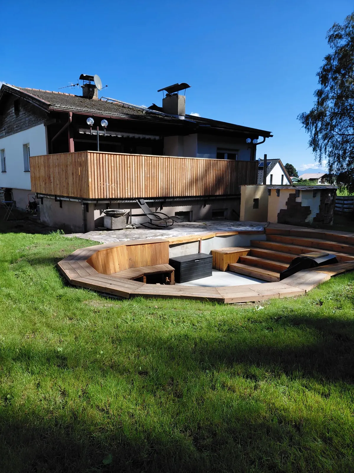 Sunken wooden deck set into the lawn in front of the house