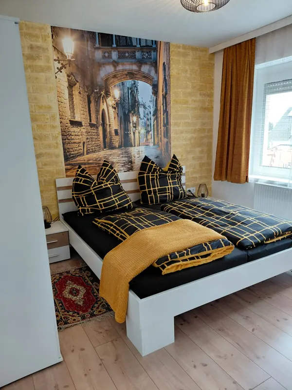 Double bed in front of a mural of an old town lane