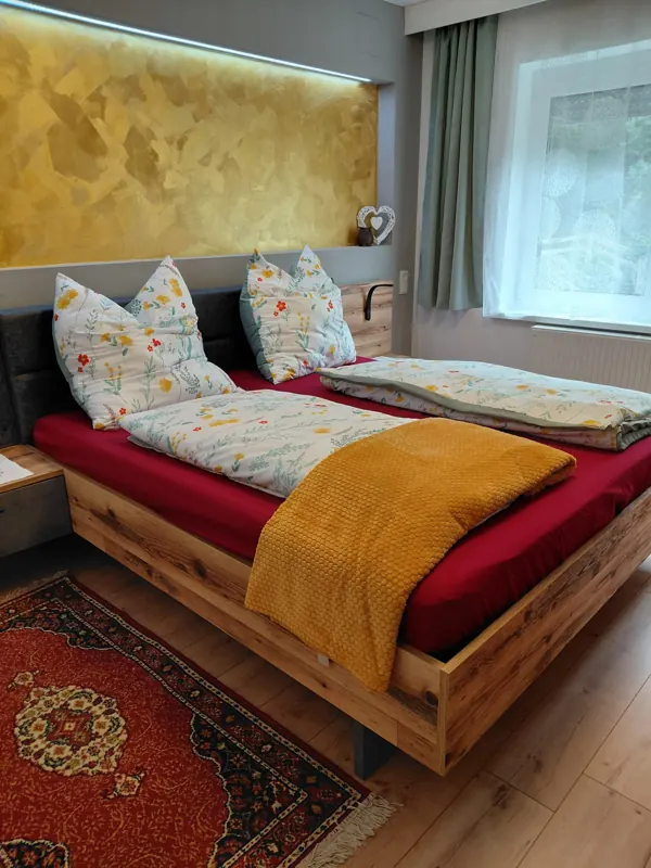 Wooden double bed with floral bedding and a yellow blanket