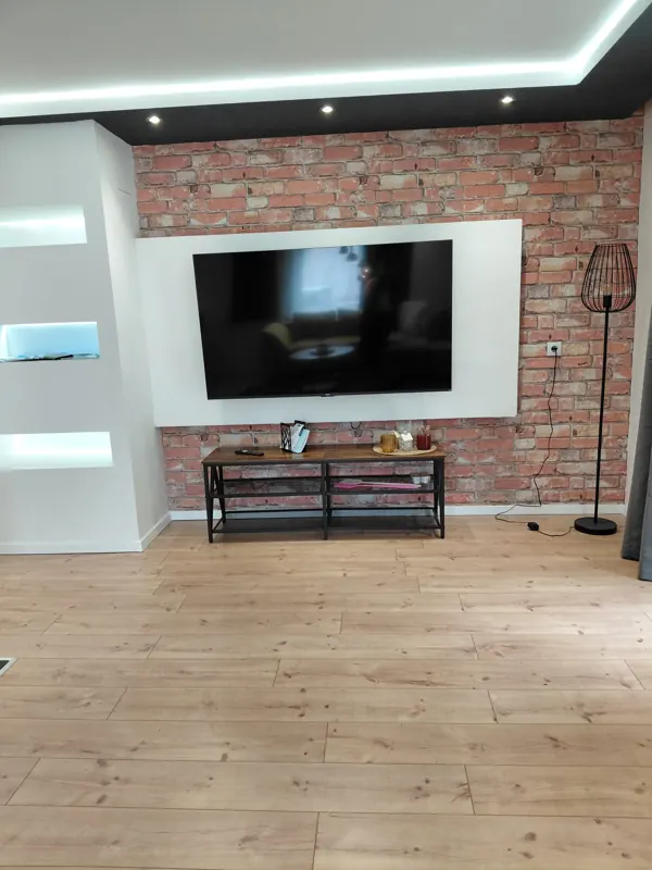 Large TV mounted on a brick wall with LED lighting